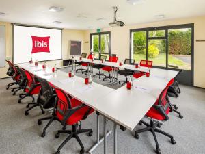 a classroom with a long table and red chairs at ibis Coventry South in Coventry