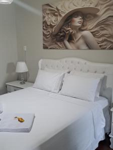 una camera da letto con un letto bianco con un dipinto sul muro di Hospedagem Altas da Quitéria Suíte 02 a Catas Altas