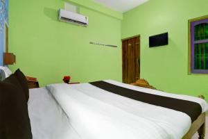 een slaapkamer met een wit bed en groene muren bij Hotel O by OYO Fakir Guest House in Puri
