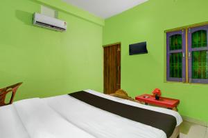 een groene kamer met een bed en een rode tafel bij Hotel O by OYO Fakir Guest House in Puri