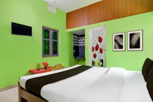 een slaapkamer met een groot bed met groene muren bij Hotel O by OYO Fakir Guest House in Puri +21 foto's