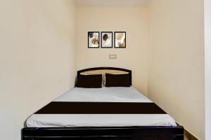 a bed in a room with two pictures on the wall at Hotel O by OYO Hill Top Hotel in Vānivilāsa Puram