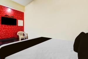 a room with a bed and a chair and a tv at Hotel O by OYO Hill Top Hotel in Vānivilāsa Puram