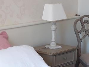 eine Lampe auf einem Nachttisch neben einem Bett in der Unterkunft eurl l'ABRICOTIER in Saint-Macaire