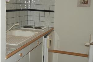 eine kleine Küche mit Herd und weißen Fliesen in der Unterkunft eurl l'ABRICOTIER in Saint-Macaire