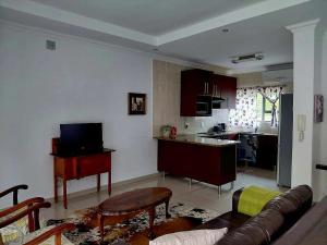 a living room with a couch and a kitchen at Agapantha Cottage in Lobamba