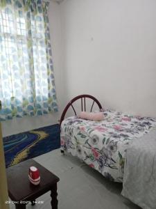 a small bedroom with a bed and a table at Homestay Casa Mutiara in Paka