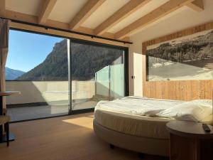 una camera da letto con un letto e una grande finestra di vetro di Liz Hotel & Apartments a Predazzo
