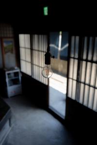 a light bulb hanging from a door in a dark room at Kashiwaya Inn in Nagiso