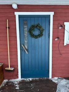 a blue door on a red house with a wreath at Guest cabin, Haukipudas, sauna and free parking in Haukipudas