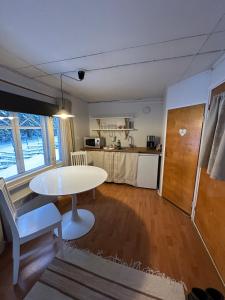 a living room with a white table and a kitchen at Guest cabin, Haukipudas, sauna and free parking in Haukipudas +20 photos