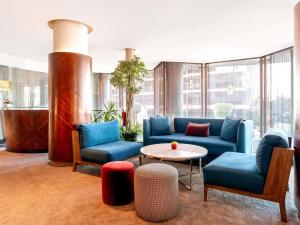 eine Lobby mit blauen Sofas sowie einem Tisch und Stühlen in der Unterkunft Le Diwan Hotel Rabat - MGallery Collection in Rabat