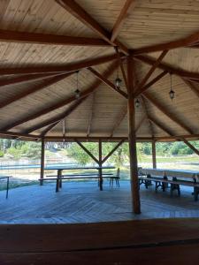 een groot houten paviljoen met banken in een park bij Bocianie Gniazdo in Bocheniec