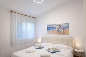een witte slaapkamer met een bed met twee borden erop bij Paradise house & garden in Lignano Sabbiadoro