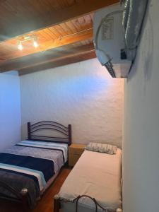 een kleine slaapkamer met 2 bedden en een televisie bij Hosteria las Palmeras in Mina Clavero