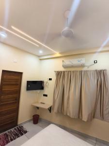 a room with a curtain and a desk and a tv at C K Residency in Cochin