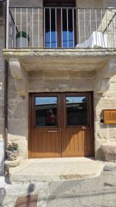 a building with a wooden door with a balcony at Casa Rural Vilar de Flores in Ourense