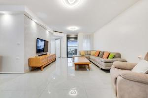 een woonkamer met twee banken en een flatscreen-tv bij Spacious Family Luxury Getaway in Ashdod
