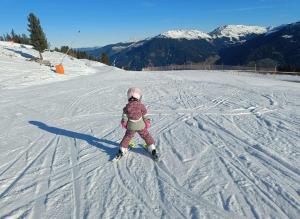 a little girl is skiing down a snow covered slope at Family & Friends in Hopfgarten im Brixental