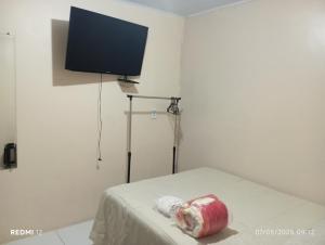 a room with a bed with a tv on the wall at kitnet A in São Luís