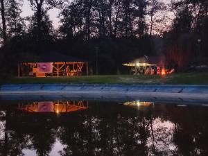 Een nachtelijk uitzicht op een tent met een vuur naast een wateroppervlak. bij Żuraw in Bocheniec