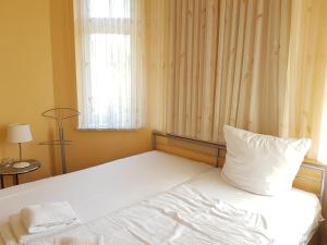 een wit bed in een kamer met een raam bij Dünenschloss - 02-29 in Kühlungsborn