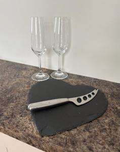 a knife sitting on a table with two wine glasses at The Knutsford Bungalow in Knutsford