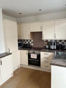 a kitchen with white cabinets and a stove top oven at The Knutsford Bungalow in Knutsford