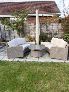 two wicker couches and a table in a yard at The Knutsford Bungalow in Knutsford +11 photos