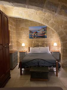 een slaapkamer met een bed in een stenen muur bij Ta' Marta Lodge in Victoria