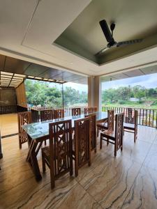 a dining room with a table and chairs and windows at Falls Regency in Kaliyal