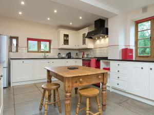a kitchen with a wooden table and two stools at Brook House in Mathon
