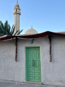 a building with a green door and a lighthouse at Timber House Dahab in Dahab