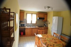 a kitchen with a table and a white refrigerator at Mirabel #2, Maisonette, terrace and pool access in Grospierres