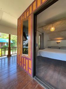 a bedroom with a bed and a large window at Spiral Resort in Ko Phayam