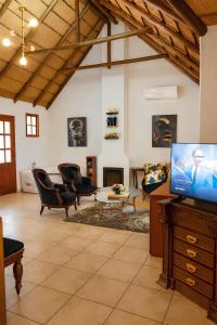 a living room with chairs and a tv in a room at The Villa Manor & Spa Exclusive Escape in Bela-Bela
