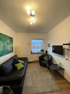 a living room with a black couch and a tv at Close to Goettingen - unweit von Göttingen in Nörten-Hardenberg