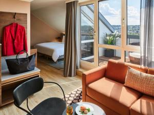 una camera d'albergo con un divano e un letto di Pullman Stuttgart Fontana a Stoccarda