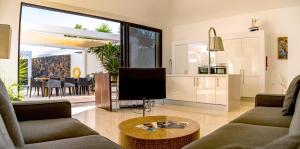 a living room with a couch and a tv and a table at Casa Paloma with heated pool in El Roque in El Cotillo