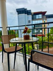 een tafel met een plant op een balkon met twee stoelen bij Sunset Statehouse View Residence in Entebbe