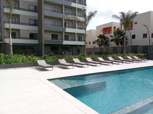 阿克拉Executive Studio at Bantree的建筑物旁边有躺椅的游泳池