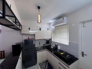 a kitchen with white cabinets and a black counter top at Zenith apartement in Trivandrum