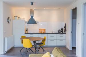 een keuken met een tafel en gele stoelen bij Landelijk appartement Friesland in Harich