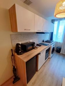 a kitchen with white cabinets and a counter with a microwave at Le studio des quais in Bergerac +10 photos