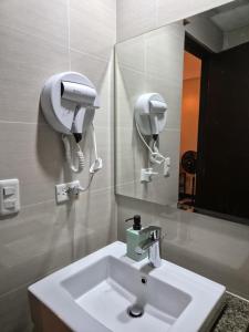 a bathroom with a sink and a hair dryer on the wall at Jacob's Place Near Manila Airport in Manila