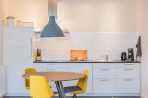 een keuken met een tafel en gele stoelen bij Landelijk appartement Friesland in Harich +16 foto's
