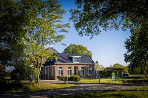een stenen huis met een zwart dak bij Landelijk appartement Friesland in Harich