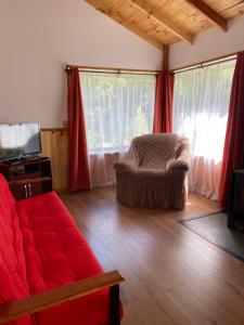 un soggiorno con un divano rosso e una TV di cabañas walls 2 a Pucón