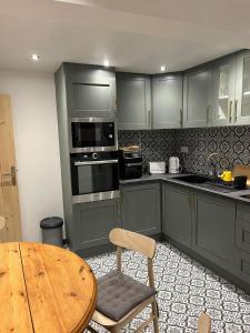 a kitchen with green cabinets and a wooden table and a table and chair at Gite St Vincent in Foix +5 photos