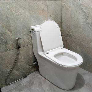 a white toilet in a bathroom with a hose at Love Bk Siargao Homestay in General Luna